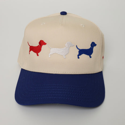 Cap with embroidered dachshunds in red, white, and blue on a beige and navy background