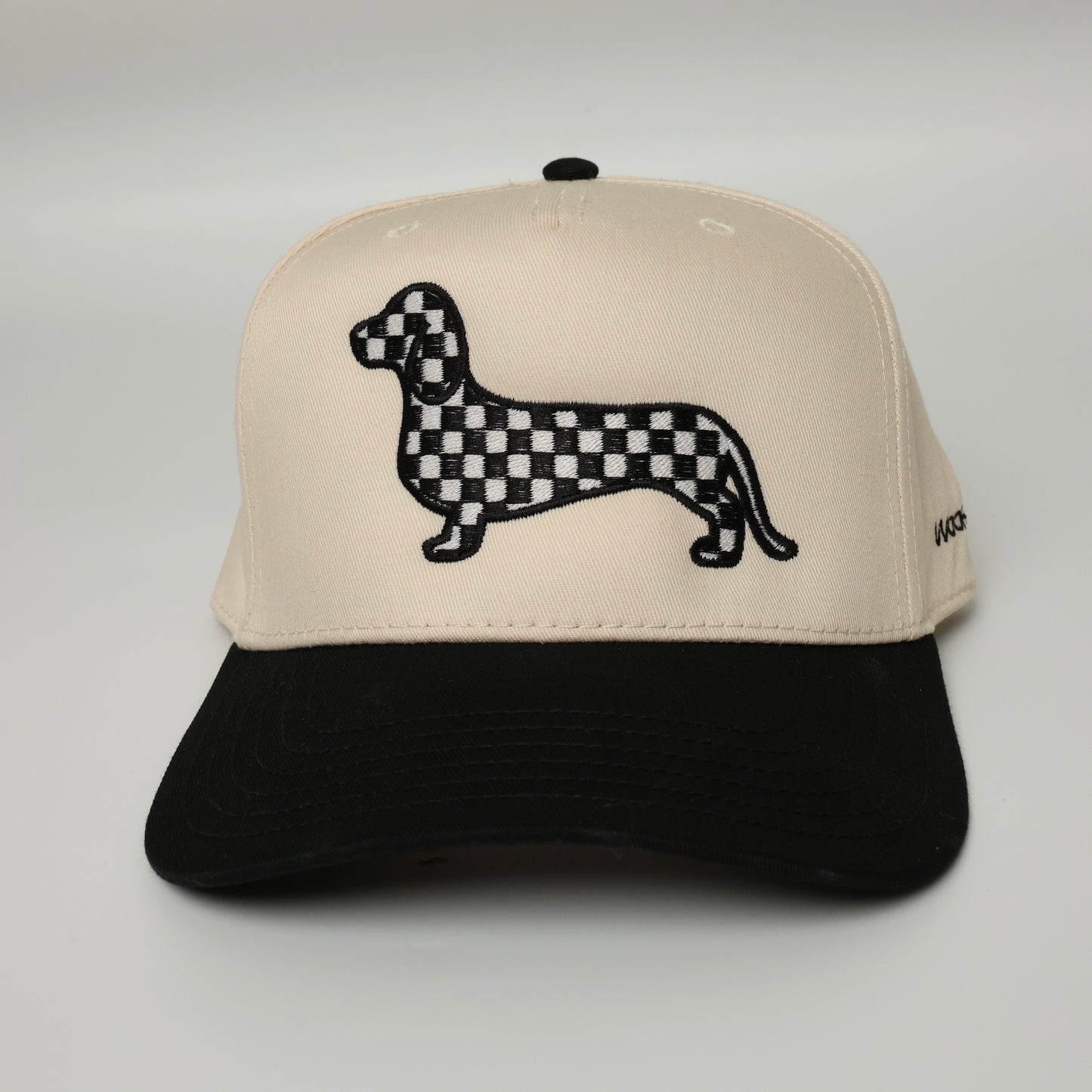 Black and white checkered dachshund embroidered on a black and beige canvas hat 
