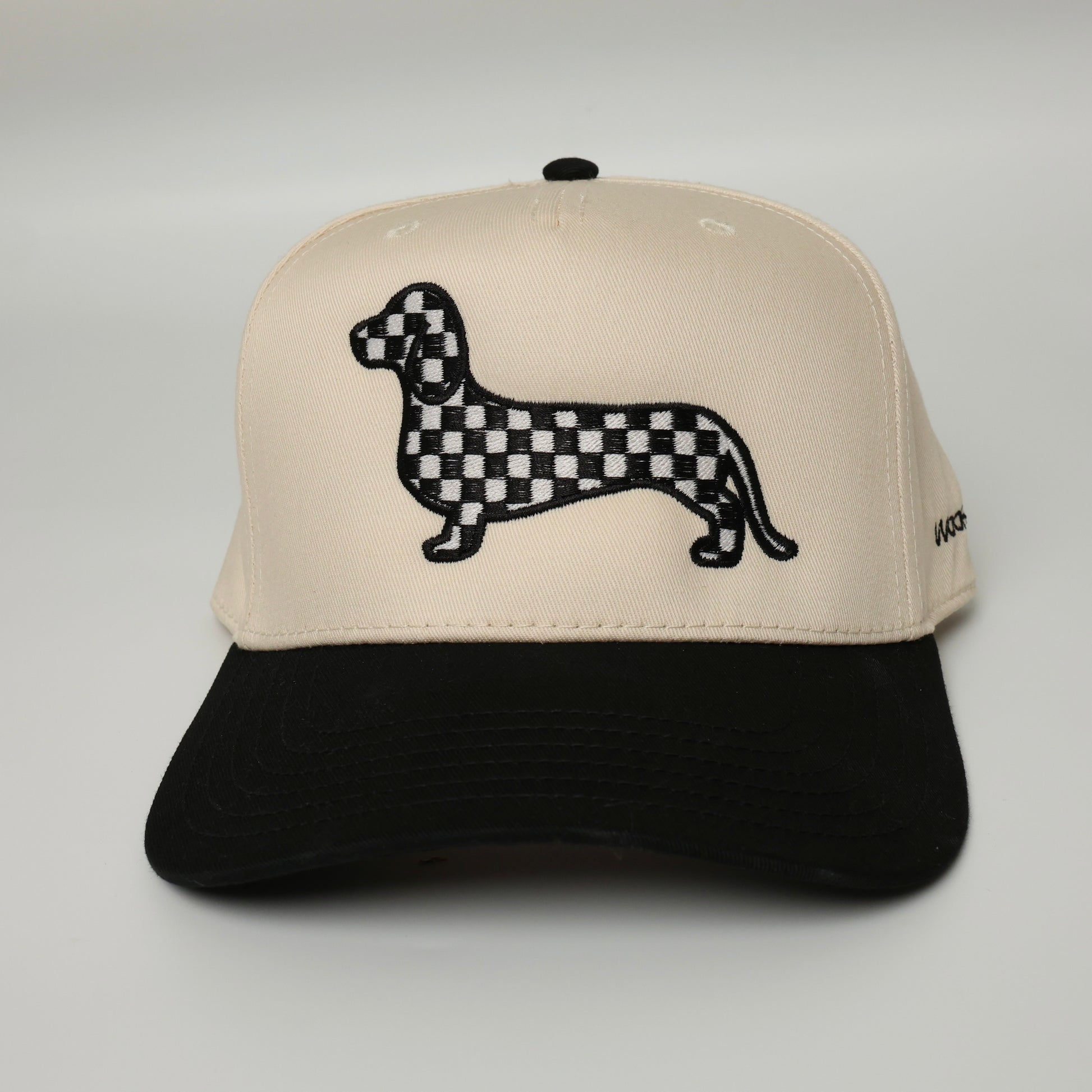 Black and white checkered dachshund embroidered on a black and beige canvas hat 