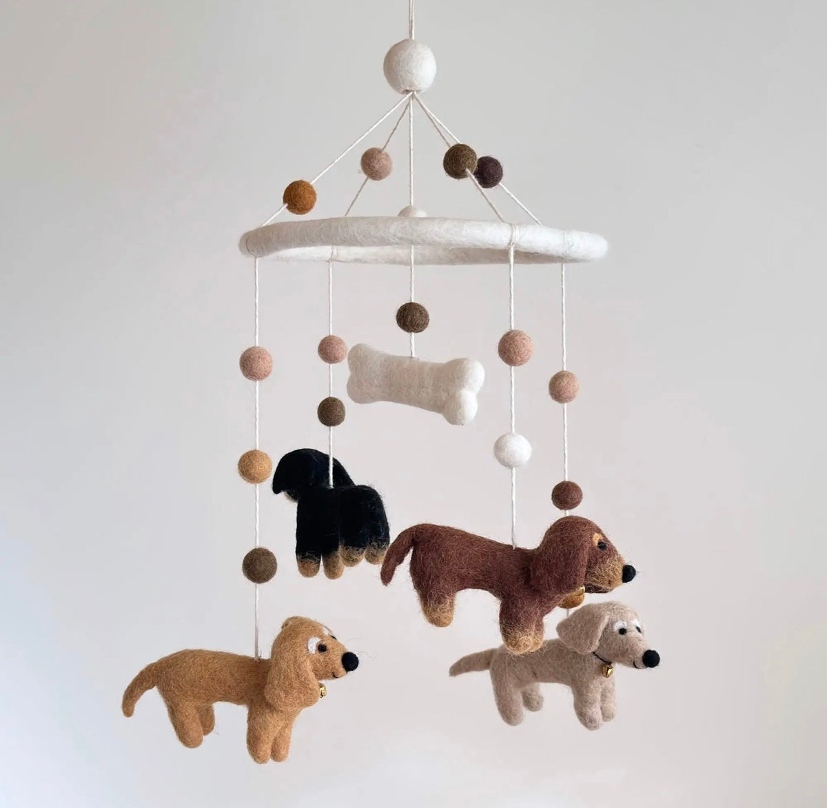 Dachshund baby mobile with four felt doxies hanging above a nursery crib