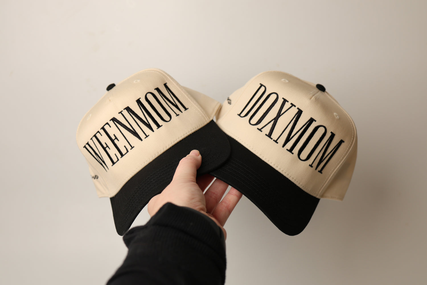 Two beige and black caps from woof+ween with 'WEEN MOM' and 'DOXIE MOM' text