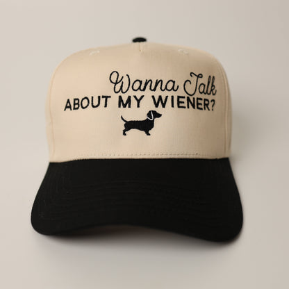 Beige and black cap with text 'Wanna Talk About My Wiener?' on a beige background